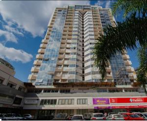 a tall building with cars parked in front of it at Luxury apartment next to Águas Claras Shopping Mall in Brasilia
