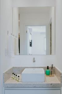 イタパリカにある2Q moderno c/ Piscina e Academiaの白い洗面台と鏡のあるバスルーム