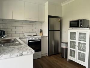 a kitchen with a sink and a stove and a refrigerator at Magnolia in Culburra Beach +17 photos