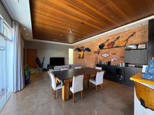 a dining room with a table and a kitchen at Oka Tupis - casa de luxo para executivos c sauna e piscina aquecida in Santa Bárbara dʼOeste