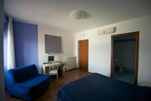 1 dormitorio con cama azul, silla y escritorio en Hotel La Bussola, en Muggia