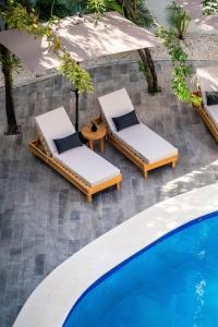 two lounge chairs and an umbrella next to a swimming pool at 18-Bed 9BD Hotel Villa - Pool & Kitchen - Full Concierge in Tulum