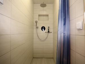 a shower with a shower head and a shower curtain at Ferienbungalow Mühlenblick in Kröpelin in Kröpelin +30 photos