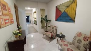 a living room with two chairs and a painting on the wall at Pousada Hangar- Seu familiar e aconchegante espaço em Belém in Belém