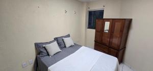 a bedroom with a bed with two pillows and a cabinet at Linda Casa 3 suítes in Belém