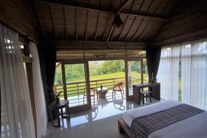 a bedroom with a bed and a balcony with a table at Dukuh Ubud Villa in Payangan