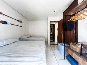 two beds in a room with a tv at Onda76 Ap temporada Praia Grande Beira Mar churrasqueira carvão in Praia Grande