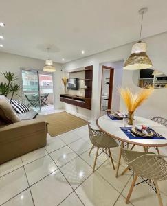 a living room with a couch and a table and chairs at Onda76 Ap temporada Praia Grande Beira Mar churrasqueira carvão in Praia Grande