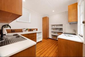 une cuisine avec des comptoirs blancs et des armoires en bois dans l'établissement Historic CBD Miner's Cottage, à Brisbane