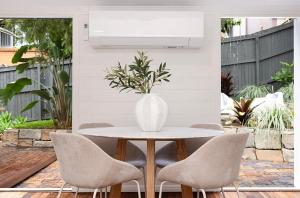 un vase blanc assis sur une table avec des chaises dans l'établissement Historic CBD Miner's Cottage, à Brisbane 5 autres photos