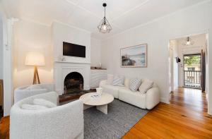Elle comprend un salon doté d'un mobilier blanc et d'une cheminée. dans l'établissement Historic CBD Miner's Cottage, à Brisbane