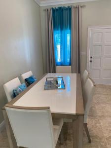 a dining room table with white chairs and a sink at Tropical Palm Townhouse in Nassau +17 photos