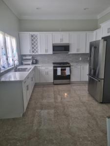 a kitchen with white cabinets and a stainless steel refrigerator at Tropical Palm Townhouse in Nassau