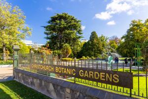 a sign for the conservatories botanic gardens on a fence at Hotel Give in Christchurch