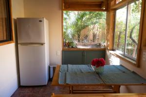 a small kitchen with a table and a refrigerator at El jardín secreto Pisco Elqui in Pisco Elqui