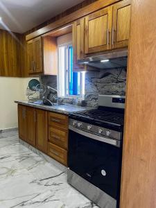 a kitchen with wooden cabinets and a stove top oven at 5 minuto de la playa C/piscina y yacuzzi in Sabana Grande