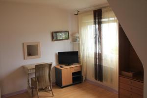 a living room with a television and a desk with a chair at Chambres d'hôtes de Pont C'Hoat in Névez