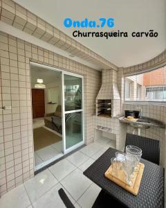 a kitchen with a table with glasses on it at Onda76 Ap temporada Praia Grande Beira Mar churrasqueira carvão in Praia Grande
