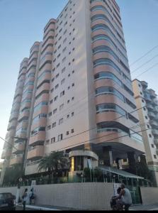 a large building with a man riding a bike in front of it at Onda76 Ap temporada Praia Grande Beira Mar churrasqueira carvão in Praia Grande