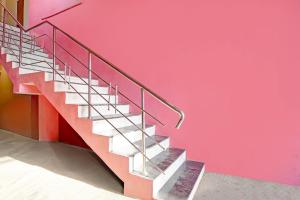 a metal staircase in a building with a pink wall at Hotel O Galaxy Stay in Chandrapur +22 photos