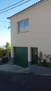 una casa blanca con una puerta verde de garaje en Maison Zita, en Venda do Atalhinho