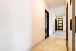 Un pasillo vacío con paredes blancas y una puerta. en Hotel O Mrinmoyi Guest House, en Kulti