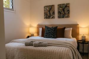 a bedroom with a bed with two paintings on the wall at The Waratah House - Modern Coastal Retreat near Cafes & Beach in Mona Vale