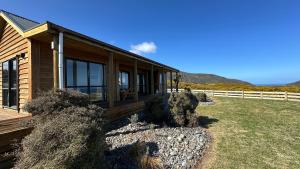 Ce chalet en bois dispose d'une terrasse couverte et de quelques buissons. dans l'établissement Paiaka Suite - The Perfect Getaway, à Lower Hutt