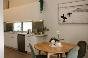 a kitchen with a wooden table and a dining room at The Waratah House - Modern Coastal Retreat near Cafes & Beach in Mona Vale