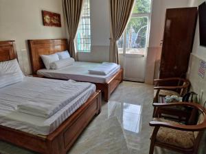 a bedroom with two beds and a chair and a window at Hostel Luxury Sài Gòn in Rạch Giá