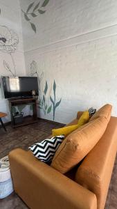 a living room with a brown couch and a tv at Increible Departamento en Ciudad de Mendoza, a metros de Parque Central y proximo a microcentro con cochera Pellegrini Apartments Parque Central in La Cieneguita +35 photos