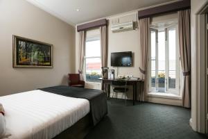 a hotel room with a bed and a desk and window at Oscars Hotel and Cafe Bar in Ballarat