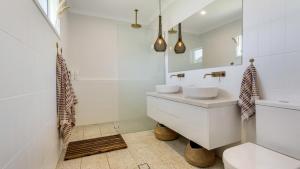 un bagno bianco con lavandino e specchio di Bangalow Breeze - Lovely Pool - Walk to Centre a Bangalow