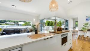 una cucina con mobili bianchi e un soggiorno di Bangalow Breeze - Lovely Pool - Walk to Centre a Bangalow