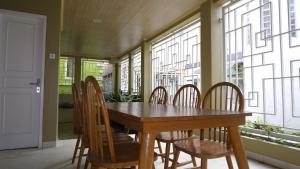 a wooden table and chairs in a room with windows at Villa Dalia Puncak K3-2A in Puncak