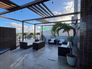 un patio con sofás y un árbol en maceta en un edificio en Flat Season com Jacuzi, en Porto de Galinhas