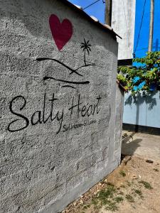 a wall with a sign that reads salty heart at Salty Heart - Surf House in Weligama