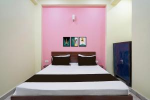 a bed in a room with a pink wall at Hotel O BLISS INN in Chinhat