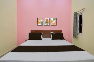 a bed in a room with a pink wall at Hotel O BLISS INN in Chinhat