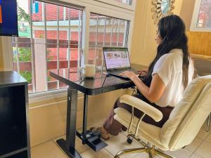 eine Frau, die an einem Schreibtisch mit einem Laptop sitzt in der Unterkunft Loft Moderno in Puerto Barrios