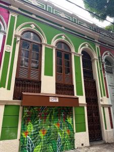 een groen gebouw met een muurschildering op de voorgevel bij Mangueirosa Hostel in Belém +31 foto's