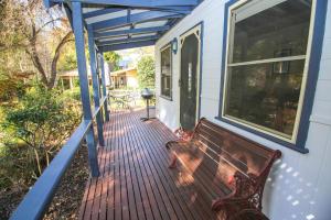 a wooden porch with a bench on a house at Autumn Leaf Cottage 2 in Harrietville