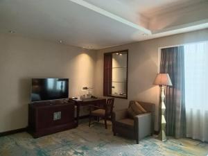 a living room with a television and a chair and a desk at Dong Fang Hotel Guangzhou - Free Canton Fair Shuttle Bus & Overseas Buyer Registration Services in Guangzhou