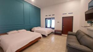 a hotel room with two beds and a couch at Riche Heritage Hotel Kayutangan Malang in Malang