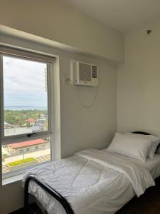 ダバオシティにあるCozy 2Br Condo Unit with Balcony Viewsの窓の横にベッドがある寝室 +23枚の写真