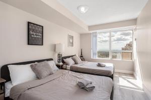 Un dormitorio con dos camas y una ventana. en SkyView 2BR Plus Den Stunning Views Steps to SQ1 Mall, en Mississauga