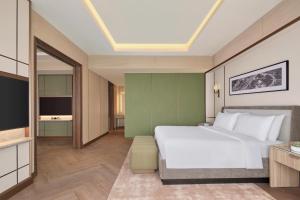 a bedroom with a white bed and a television at JW Marriott Hotel Jakarta in Jakarta