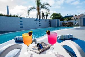 two cocktails on a table next to a swimming pool at * - The Leucadia Beach Grotto - * An Encinitas Gem in Encinitas