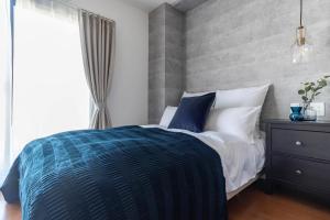 a bedroom with a blue and white bed and a window at Villa Penthouse Tenma in Osaka
