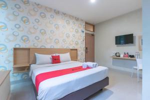 una camera da letto con un grande letto con un asciugamano rosso di Sans Stay Karapitan Street a Bandung Altre 30 foto